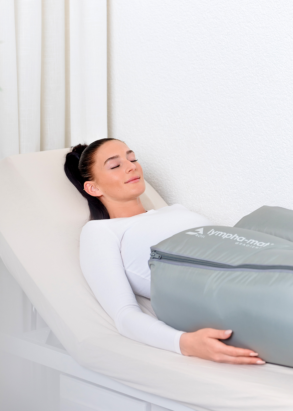 eine braunhaarige Frau liegt in der apparativen lymphdrainage